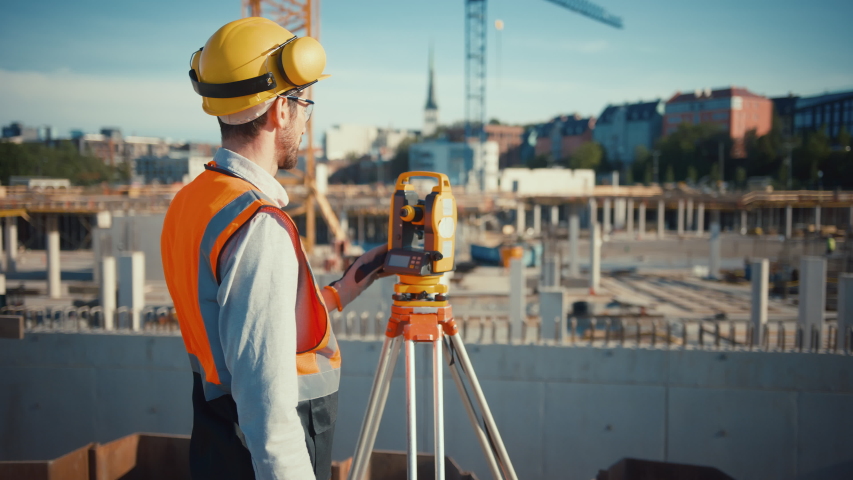 Construction Worker Using Theodolite Surveying Optical Instrument for Measuring Angles in Horizontal and Vertical Planes on Construction Site. Worker in Hard Hat Making Projections for the Building. Royalty-Free Stock Footage #1057388371