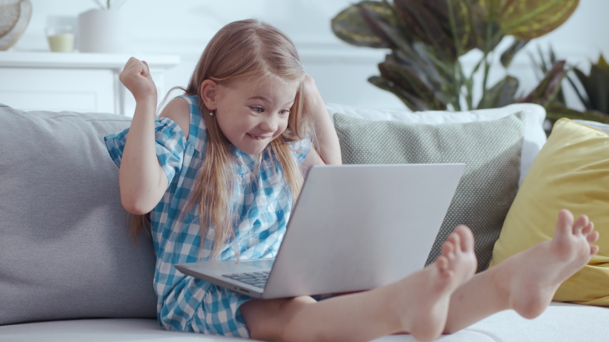 Sweet pretty preschool girl staying home playing video games using laptop with excitement winning cheering up enjoying leisure. Home technology. Children. Kids. Royalty-Free Stock Footage #1057389034