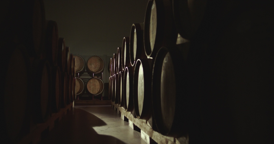 Worker in wine , whiskey or brandy warehouse sorting and rotating barrel . Two winemakers in vintage , traditional wine factory rolls barrel . Shot on ARRI ALEXA Cinema Camera in Slow Motion .