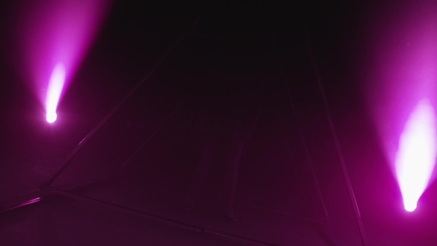 Stylish young man standing inside led triangular lights with real strobe. Against purple background with a triangle shape of led lights. Shot on RED Cinema Camera in slow motion.
