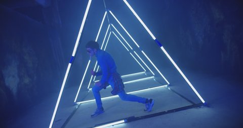 4K Professional Hip Hop break dancer . Stylish young man dancing with real strobe lights . Against blue background with triangle shape of led lights . Real decoration . Shot on RED EPIC Cinema Camera