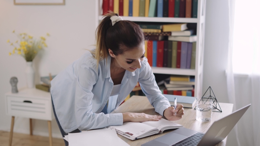 Young woman wears headset conference calling on laptop talks with online teacher studying, working from home. Lady student e learning using computer webcam chat makes notes. Distance education concept Royalty-Free Stock Footage #1057396363