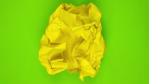 Stop motion animation. Yellow paper unfolds from a paper ball and then wrinkles and disappears
