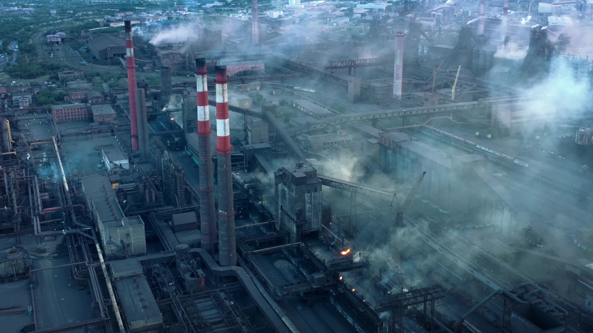 Drone aerial shot factory tubes and chimneys. Fly over pan circular shot of industrial zone, grey and foggy sky, health risk area. Environmental problems, air pollution Royalty-Free Stock Footage #1057404994