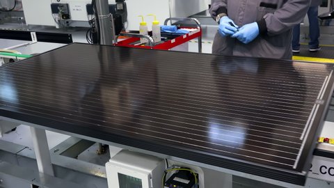 A Modern Factory Worker Wipes The Solar Panel In A Modern Photovoltaic Factory