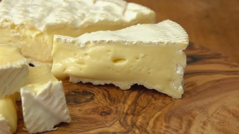 Close-up panorama of a delicious piece of soft brie cheese taken from a wooden board with a fork