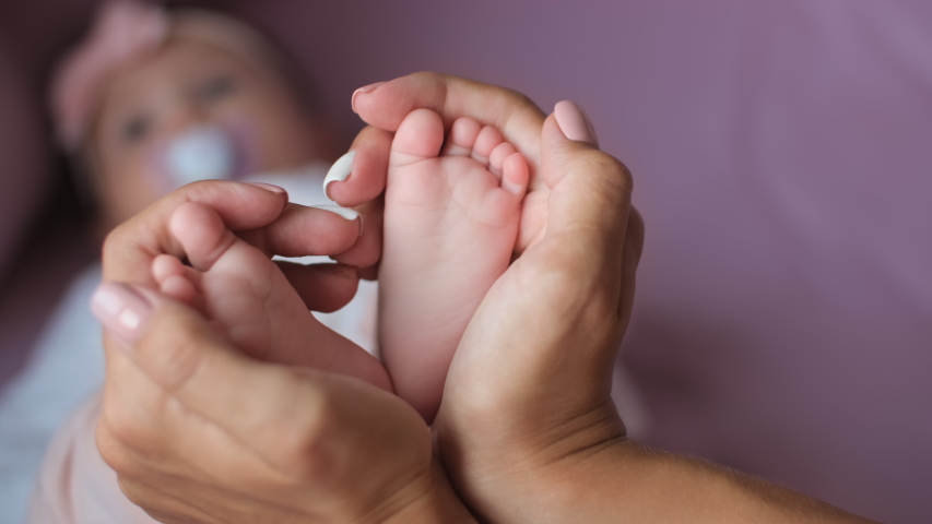 Newborn baby, Care and Love, Portrait of a Child. Mom holds baby feet in her hands forming a heart shape