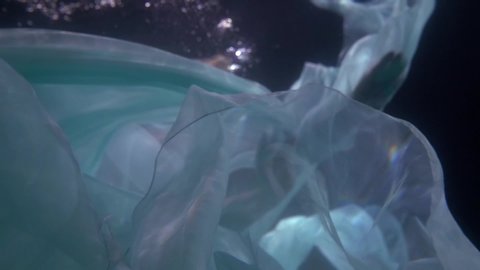 mysterious woman is floating underwater and playing with white fabric, magical mermaid