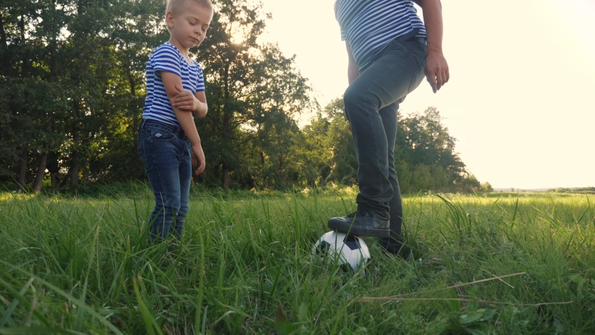 father and son playing football soccer in the park on the grass. happy family dream kid concept. dad and boy play ball outdoor sports in the park lifestyle healthy. parent plays with son into ball Royalty-Free Stock Footage #1057410925