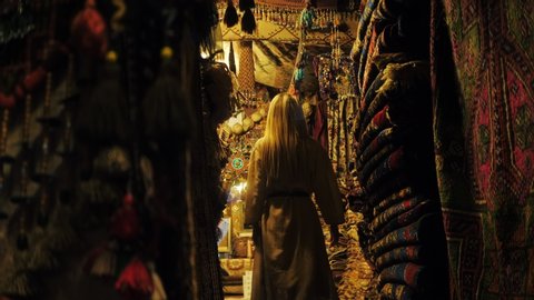 Fashion blonde beautiful girl in old carpet shop walking seductive. Turkey. Oriental carpet. Persian shop. Tourists in store.