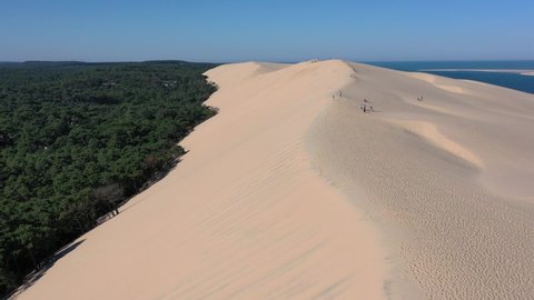 Overview of Dune du Pilat Sandhill in Arcachon Bassin France with People walking along the top ridge, Aerial flyover shot