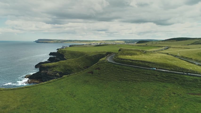 Green fields, meadows aerial: road cars driving on background. Ireland's hills, farmlands, clouds on horizon. Picturesque landscape view of Antrim County, United Kingdom. Footage shot in 4K, UHD | Shutterstock HD Video #1057416877