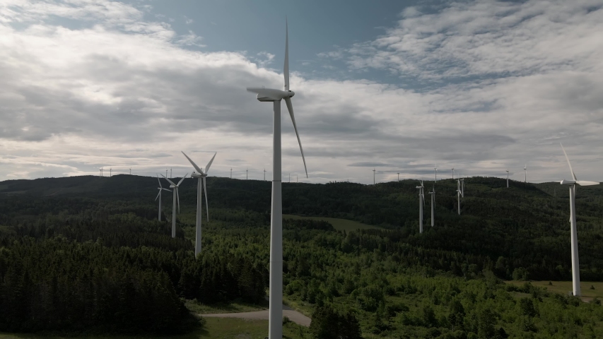 Wind Turbines Generating Renewable Energy On The Lush Field In Canada On A Sunny Day - elevated panning shot