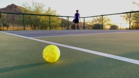 Focus on a Pickle ball with Woman Playing in the Background