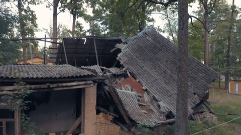 Abandoned single-family home (detached home or detached house) with broken windows and burnt destroyed roof among a forest