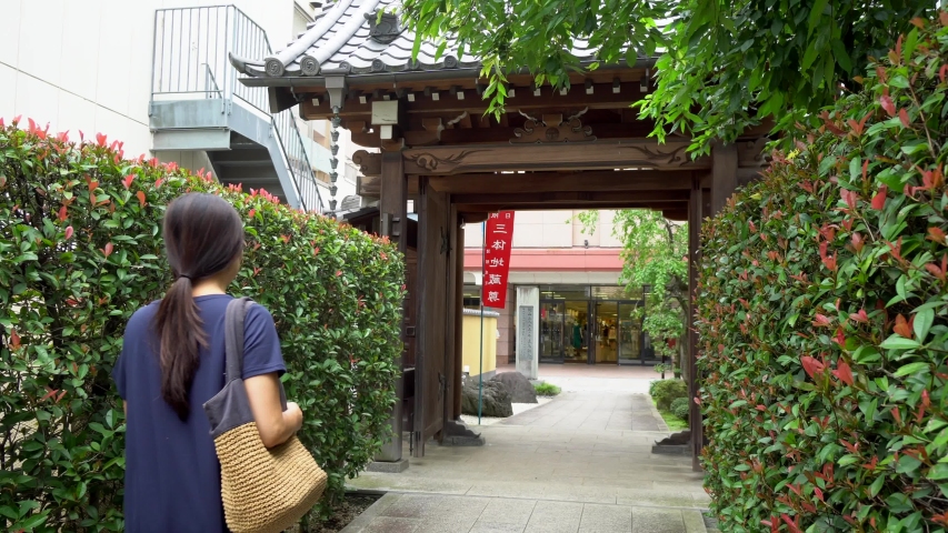A Japanese woman walks along the path out of a Busdist temple in the traditional Kawagoe neighborhood of Tokyo, Japan. This neighborhood is one of the oldest in Tokyo, also called Little Kyoto.