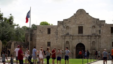 San Antonio , Texas / United States - 07 14 2018: The Texas State flag flutters in a gentle breeze on a warm summer day, as tourists visit the famous and historic Alamo, in San Antonio, Texas as captu