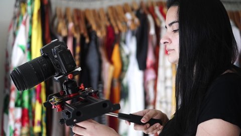 Woman photographing with a digital single lens reflex camera. Girl power. Freelance job. Caucasian female in a photography business. Clothing store environment.