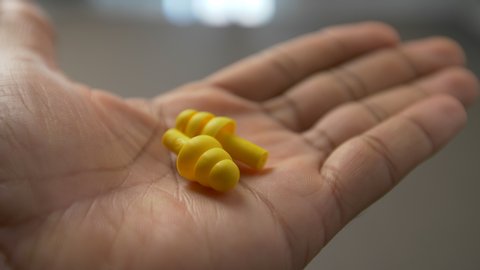 Holding a pair of earplugs in the palm of the hand.