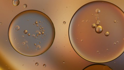 Gold artistic of oil drop floating on the water. Pastel color bubble for background. Orange background of oil drop.