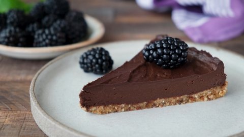 Chocolate mousse tart decorated with blackberries. Taking bite of pie with a fork