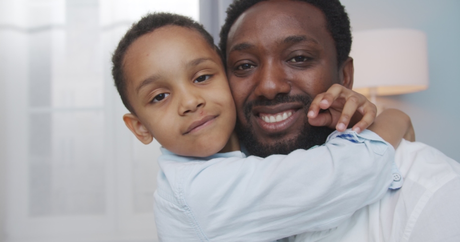 African American happy family. Joyful little cute boy hugging his smiling father at home. Handsome cheerful man with adorable nice boy indoors. Dad and son relations. Close up concept | Shutterstock HD Video #1057432006
