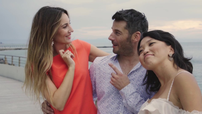 Three friends embracing on promenade