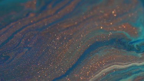 Blue, turquoise and copper colors mix. Paint movement. Ink flow. Glitter fluid motion. Moving flowing stream of liquid paint