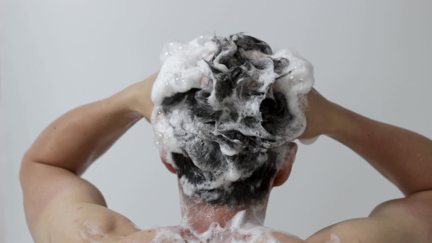 A man washes his head with shampoo on white background, rear view Royalty-Free Stock Footage #1057434196