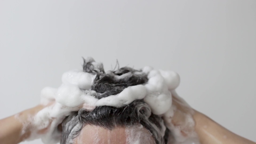 A man washes his head with shampoo on white background, front view Royalty-Free Stock Footage #1057434199