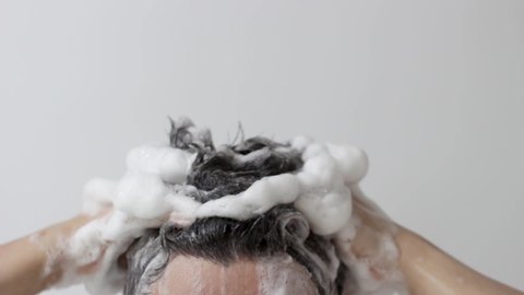 A man washes his head with shampoo on white background, front view