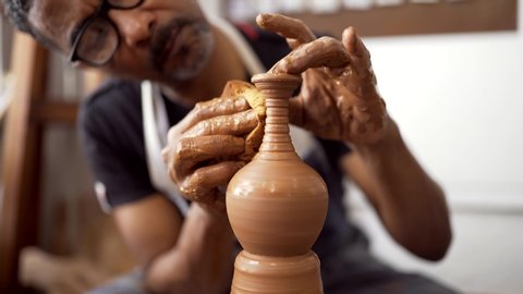 Hands of man at pottery wheel forming clay using sponge
