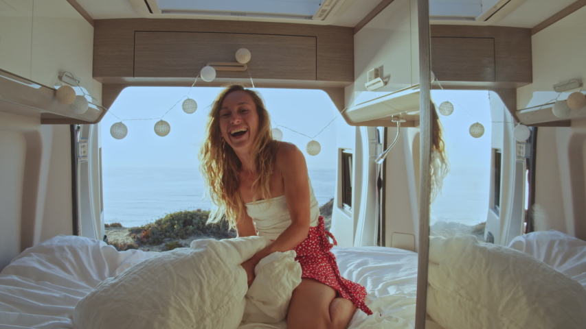Point of view, couple having pillow fight in the back of a camper van. Alternative living, woman in bed with sea views playing with pillow | Shutterstock HD Video #1057437907