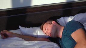 man sleeping in a bed with the sun shining in his face