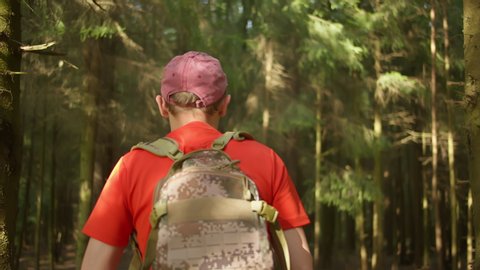 Male tourist with a backpack walks through the forest, camera tracking