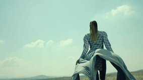 Rear view of woman walking in slow motion through a field . Young stylish lonely girl walking on meadow field . Long skirt fabric flowing by wind . Fashion style . Shot on ARRI Alexa Cinema Camera