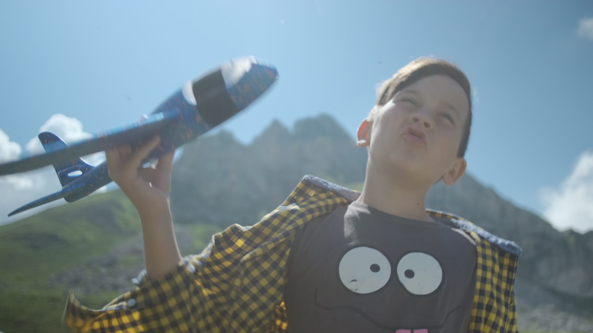 Happy little boy playing with a toy blue plane on a background of mountains in Montenegro. Happy childhood concept. 
