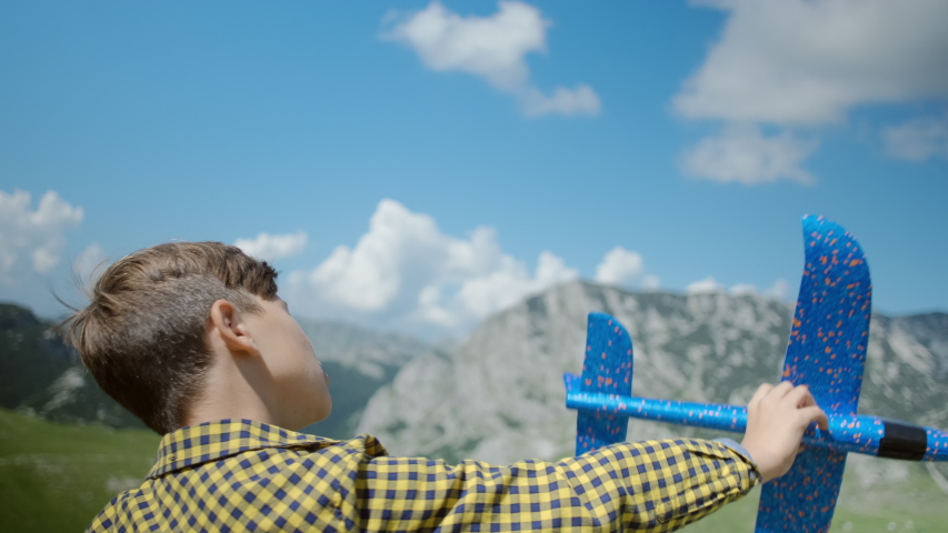 Happy little boy playing with a toy blue plane on a background of mountains in Montenegro. Happy childhood concept. 
