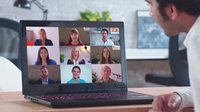 Online distance learning video conference webinar call remote work webcam meeting concept. Back view middle-eastern man talk to 9 diverse colleagues team business partner coach at laptop home