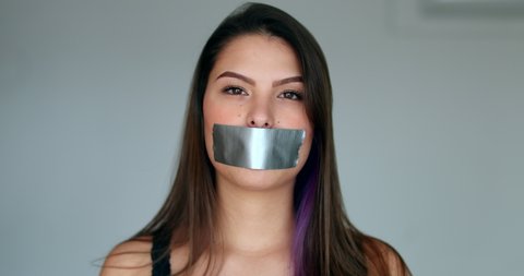 Assertive woman removing tape from mouth feeling relief and freedom to speak