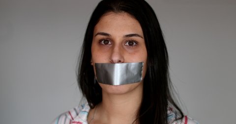 Silenced young woman having her voice shut mouth taped.