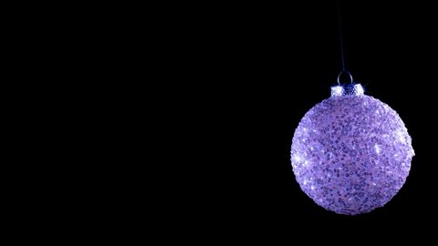 Festive ball on a dark background. New Year tree and holiday concept. The ball spins and glitter. Tree decorations moves on a string.