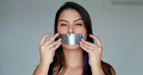 Young woman putting mouth tape. Censored pretty woman unable to speak, censorship concept
