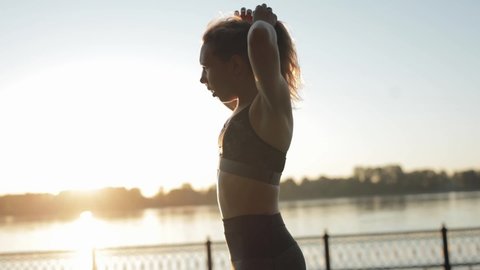 Female gets up and gets ready to run in the morning at dawn. Close up of young active woman getting ready to start fitness workout in urban environment outdoors.