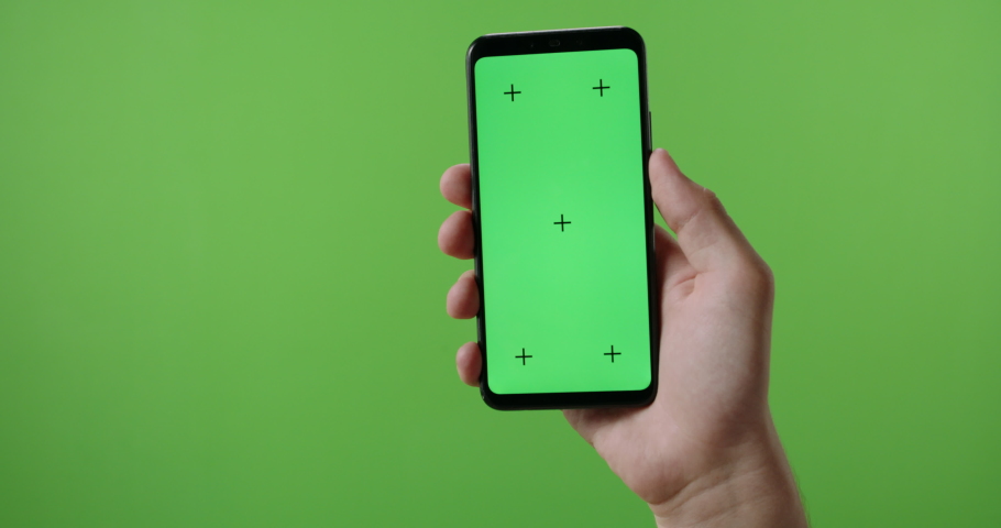 Hands of man holding a phone with vertical green chroma key screen. isolated on green background, swiping the touchscreen 4k template Royalty-Free Stock Footage #1057452715