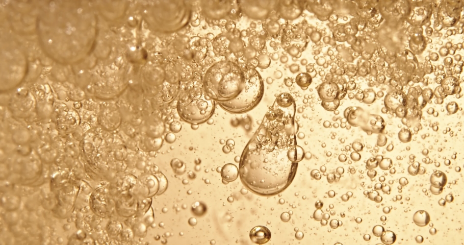 Fuel, oil, yellow golden hue, with moving bubbles, up and down, in the glass vessel of the laboratory. Copy space. Macro oil and water interacting Royalty-Free Stock Footage #1057459420