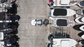 Over head view on loader carefully lifting the yacht at the multi-level boat parking. Beautiful slow motion drone video for yacht business. 4K aerial video of water transportation, Miami port, Florida