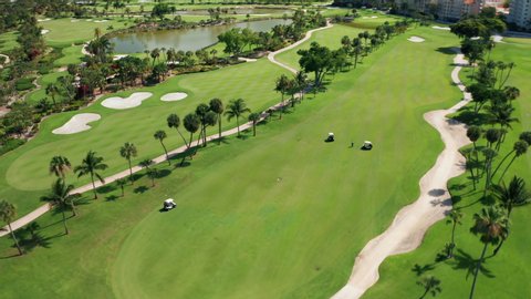 Golf course 4K. Aerial footage of people on a golf field playing the sport match in Miami, Florida, USA. Cinematic overhead view on active men playing the golf game on a sunny summer day. background