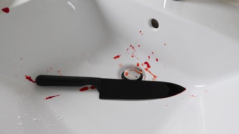 Horror crime scene. A bloody knife, murder weapon, thrown in the bathroom sink.