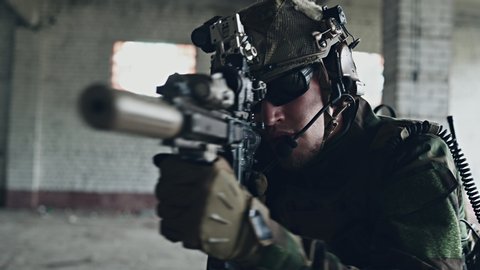 Soldier aiming and moving in with the rifle in abandoned building.